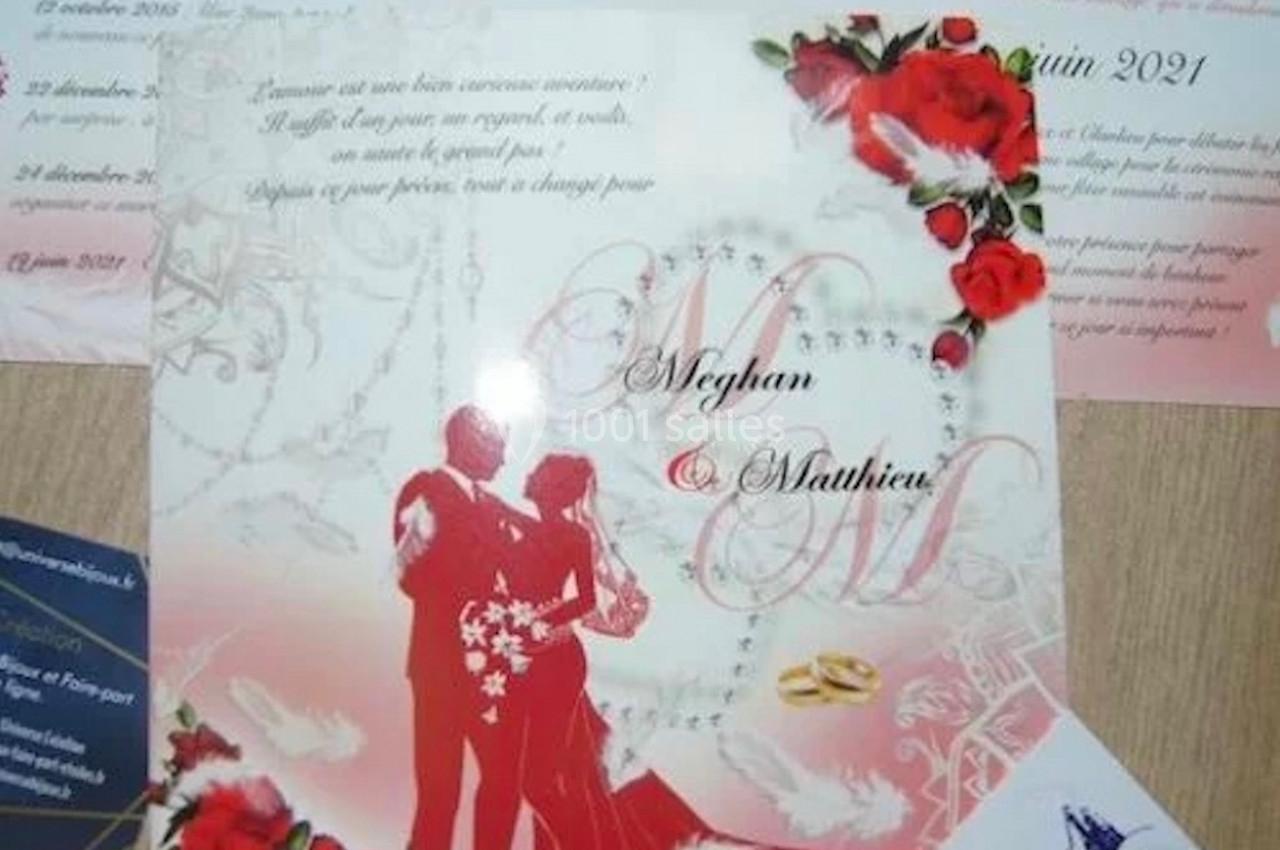 Carte d'invitation de mariage décorée de roses rouges, silhouettes d'un couple et alliances dorées.