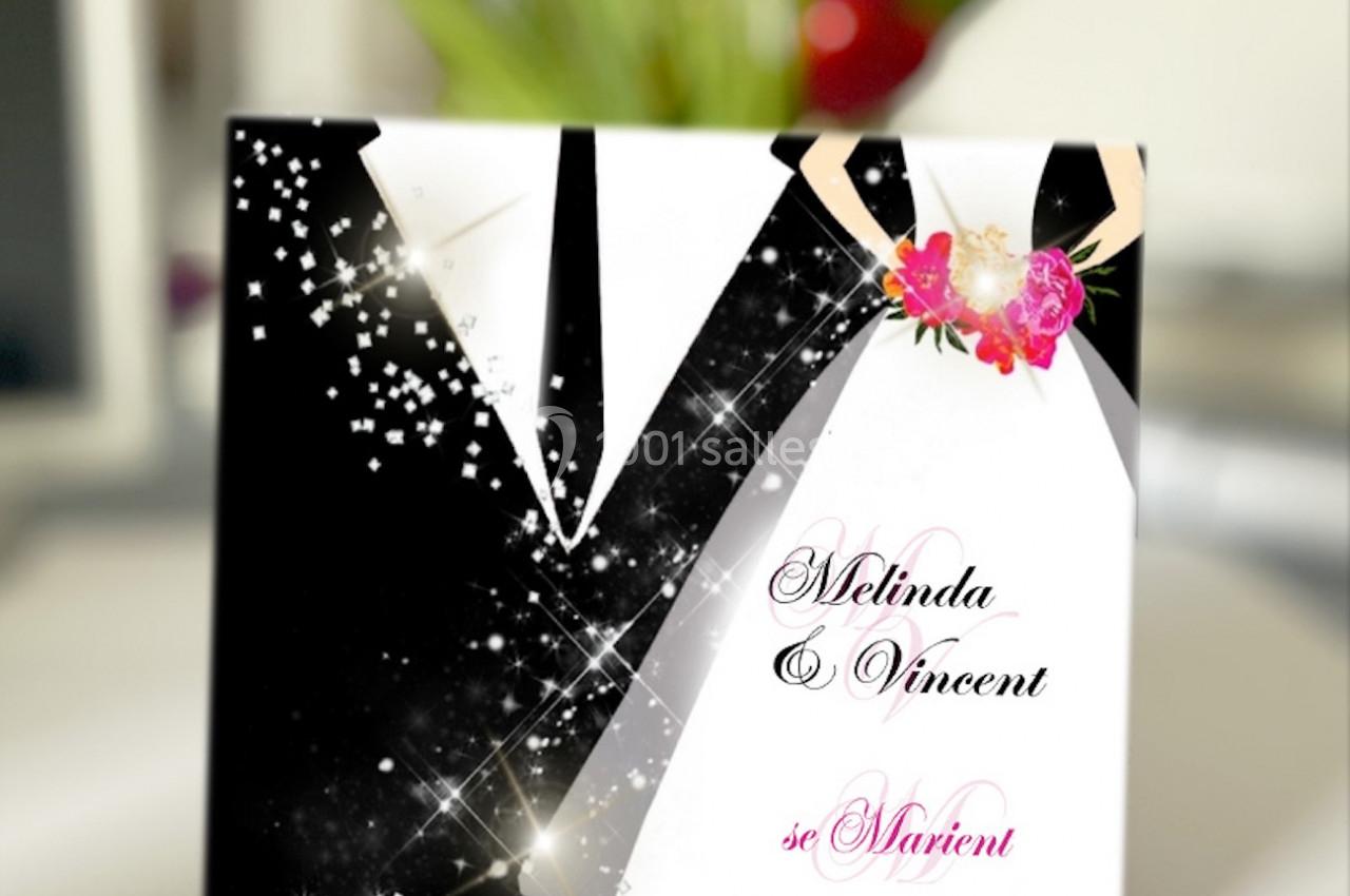 Carte de mariage avec un costume noir et une robe blanche ornés de fleurs roses et des noms écrits en calligraphie.
