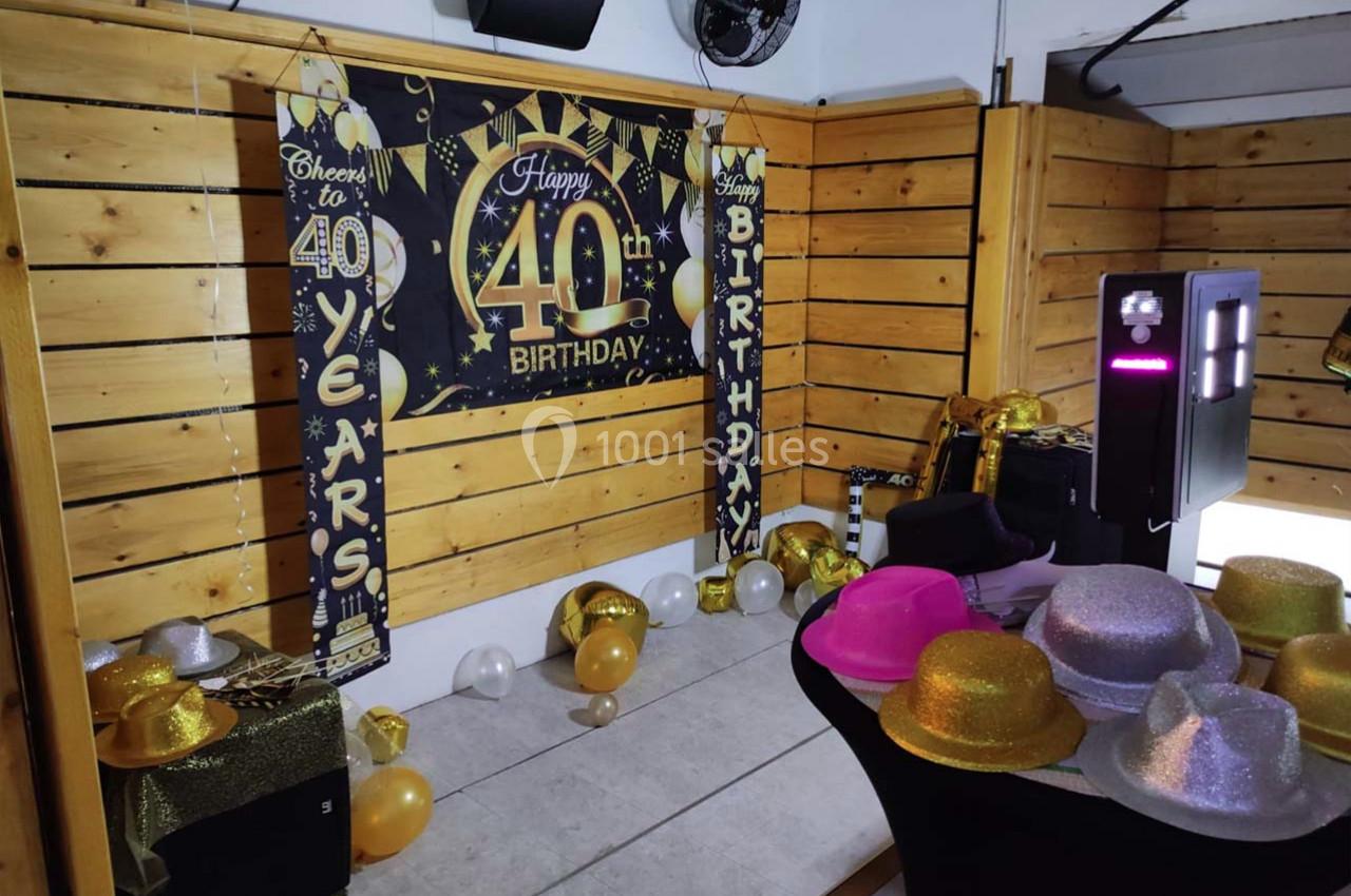 Décoration festive pour un 40e anniversaire avec ballons, bannières et accessoires colorés dans une salle en bois.