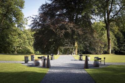 Miniature Location salle Habay (Luxembourg) - Château du Pont d'Oye #9 Façade d'une maison en pierre avec porte beige, fenêtres blanches et environnement boisé en arrière-plan.