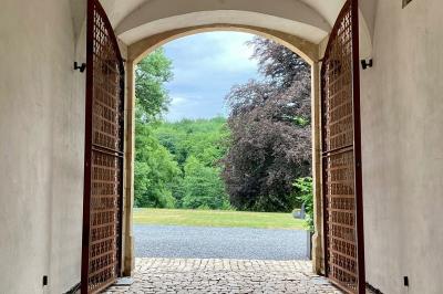 Miniature Location salle Habay (Luxembourg) - Château du Pont d'Oye #13 Façade d'une maison en pierre avec porte beige, fenêtres blanches et environnement boisé en arrière-plan.