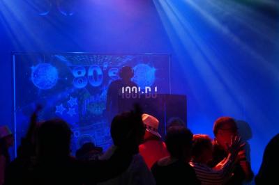 Salle de réception en pierre avec invités assis et debout, décorations florales suspendues et ambiance chaleureuse.