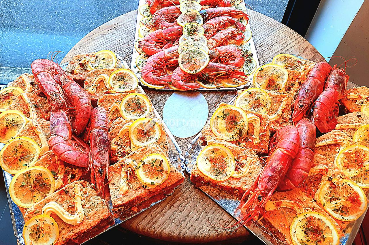 Plateaux de tartes salées garnies de crevettes, rondelles de citron et herbes, disposés sur une table en bois.