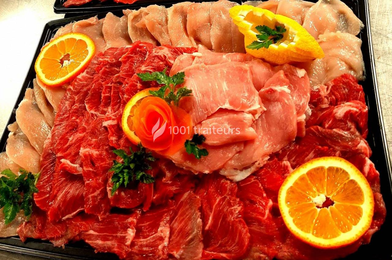 Plateau de viandes variées crues, comprenant du bœuf, du porc et du poulet, décoré d'oranges et de persil.