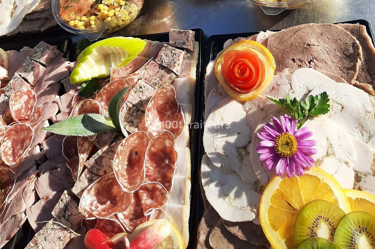 Plateaux de charcuterie variée avec tranches de viande, pâtés, fruits décoratifs et garnitures colorées.