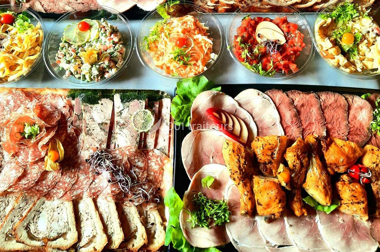 Plateau de charcuteries, viandes froides, pains et salades variées présentés sur une table.