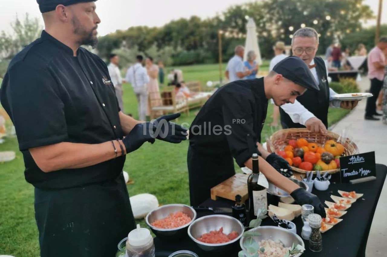 Des chefs préparent des amuse-bouches à base de tomates lors d'un événement en plein air dans un jardin.