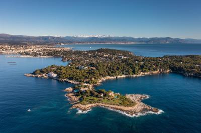 Vue aérienne d'une péninsule boisée entourée de mer, avec des montagnes enneigées à l'horizon.