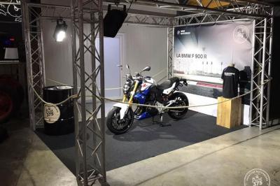 Vue nocturne d'un showroom automobile éclairé, avec une affiche promotionnelle d'un véhicule BMW X1 au premier plan.