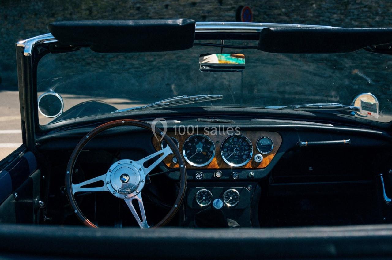 Intérieur d'une voiture ancienne décapotable avec tableau de bord en bois et volant classique.