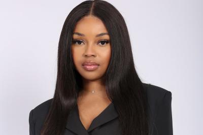 Femme portant une tenue rose satinée, posant devant un fond uni gris clair.