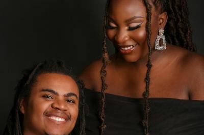 Femme portant une tenue rose satinée, posant devant un fond uni gris clair.