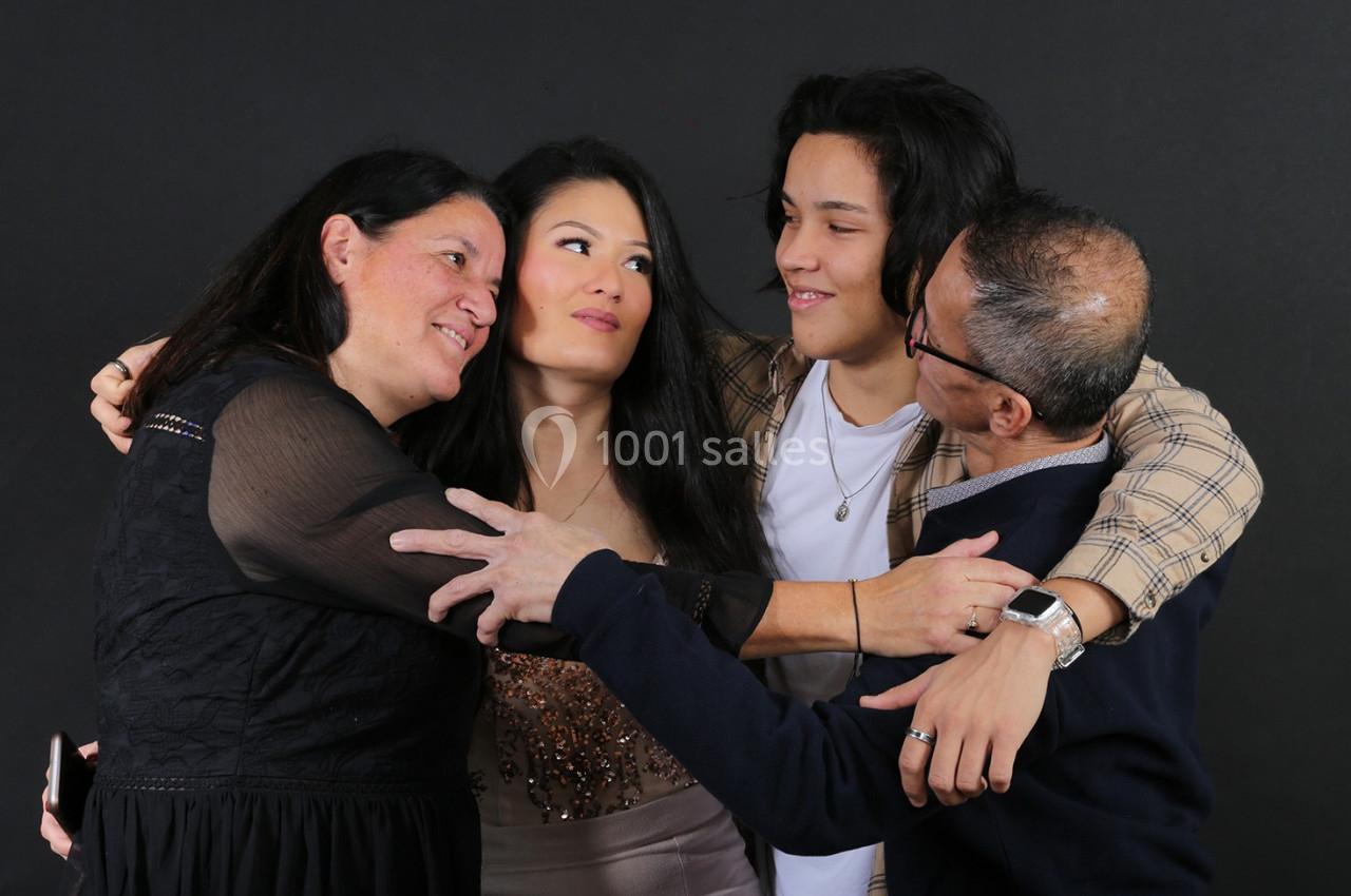 Quatre personnes souriantes s'enlaçant devant un fond noir.