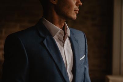 Un couple assis lors d'une cérémonie, l'homme ému essuie une larme tandis que la femme le regarde avec tendresse.