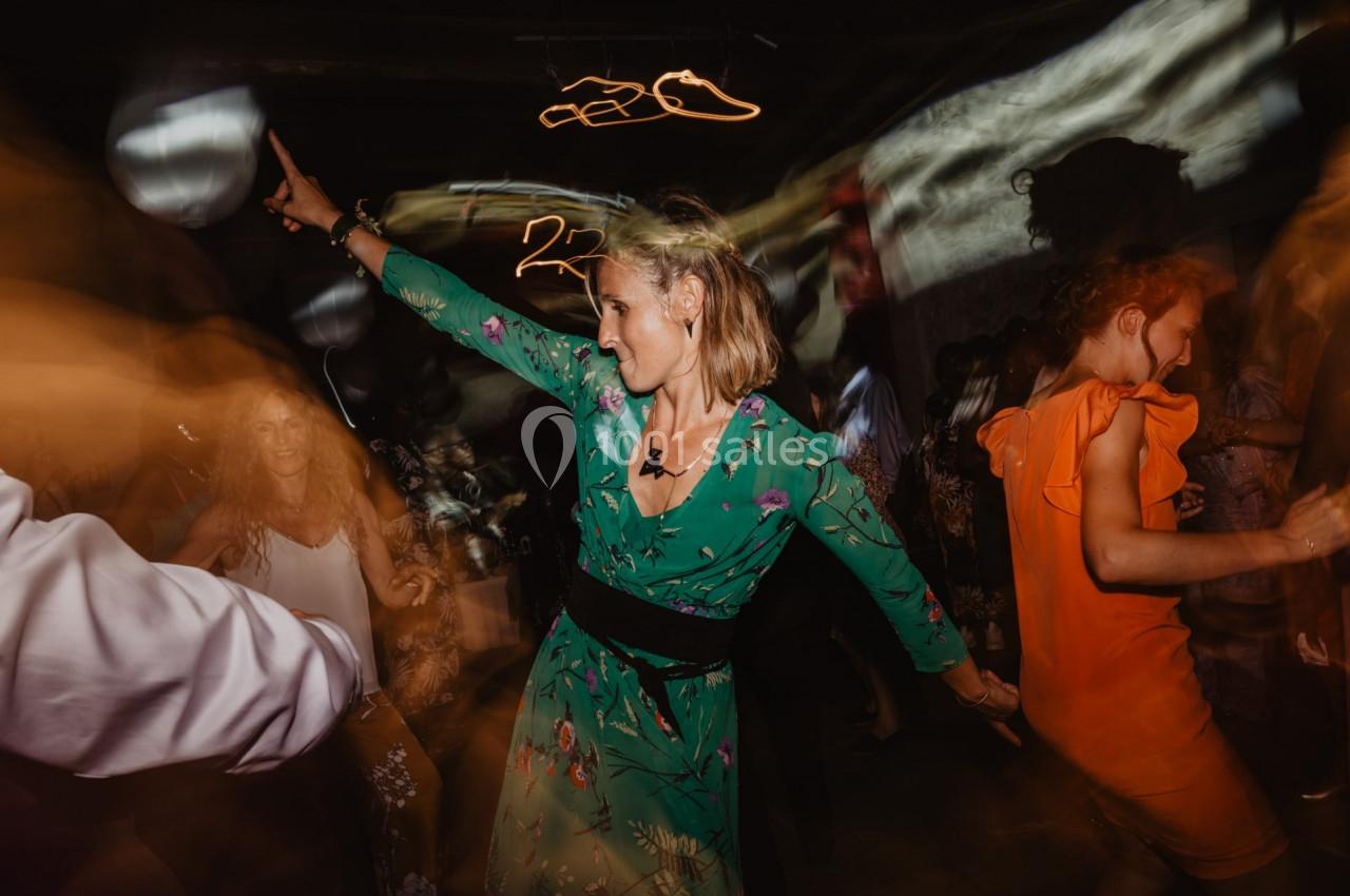 Femme en robe verte dansant au milieu d'une foule dans une ambiance festive et éclairage tamisé.