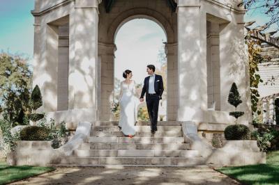 Un couple assis lors d'une cérémonie, l'homme ému essuie une larme tandis que la femme le regarde avec tendresse.
