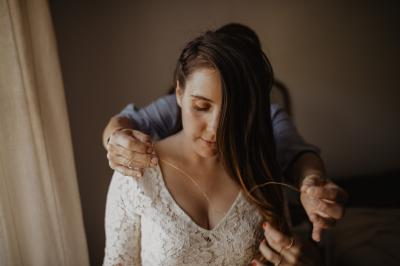 Un couple assis lors d'une cérémonie, l'homme ému essuie une larme tandis que la femme le regarde avec tendresse.