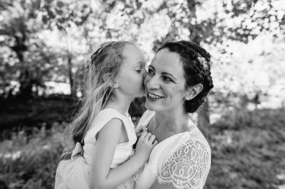 Un couple assis lors d'une cérémonie, l'homme ému essuie une larme tandis que la femme le regarde avec tendresse.