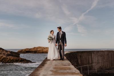 Un couple assis lors d'une cérémonie, l'homme ému essuie une larme tandis que la femme le regarde avec tendresse.
