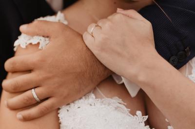 Un couple assis lors d'une cérémonie, l'homme ému essuie une larme tandis que la femme le regarde avec tendresse.