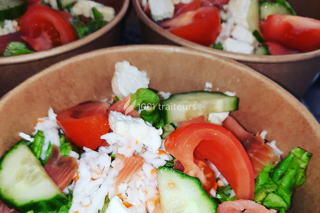 Salades composées dans des bols en carton, avec tomates, concombres, laitue, fromage et morceaux de crabe.
