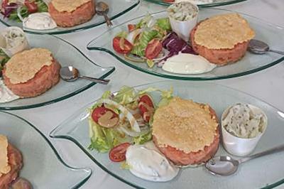 Salle de réception décorée avec des tables rondes et rectangulaires dressées pour un événement festif.