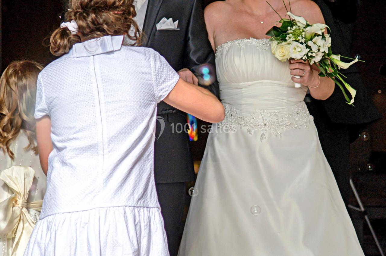 Un couple de mariés souriants entouré d'enfants, avec des bulles flottant dans l'air.