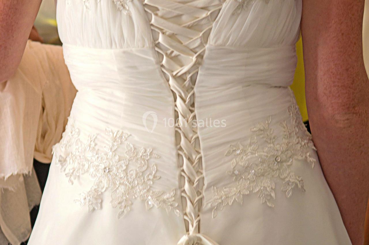 Vue arrière d'une robe de mariée blanche avec un corset lacé et des détails en dentelle.