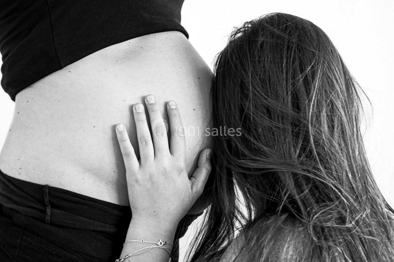 Une femme pose sa main sur un ventre de femme enceinte tandis qu'elle y pose sa tête, en noir et blanc.