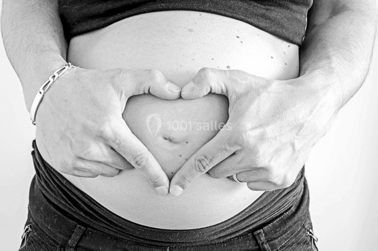 Mains formant un cœur sur un ventre de femme enceinte, symbolisant la maternité et l'amour.
