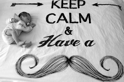 Nouveau-né dormant sur une couverture avec l'inscription ’Keep Calm & Have a’ et un dessin de moustache.
