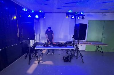 Vue depuis une table de mixage sur un groupe de personnes dansant dans une salle éclairée par une lumière rouge.