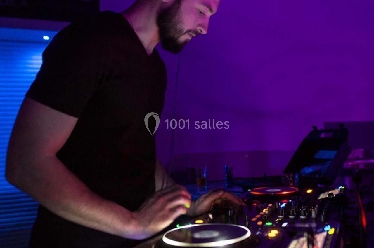 Un DJ mixant de la musique sur une table de mixage dans une ambiance lumineuse violette.