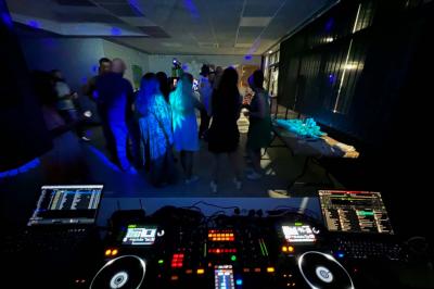 Vue depuis une table de mixage sur un groupe de personnes dansant dans une salle éclairée par une lumière rouge.
