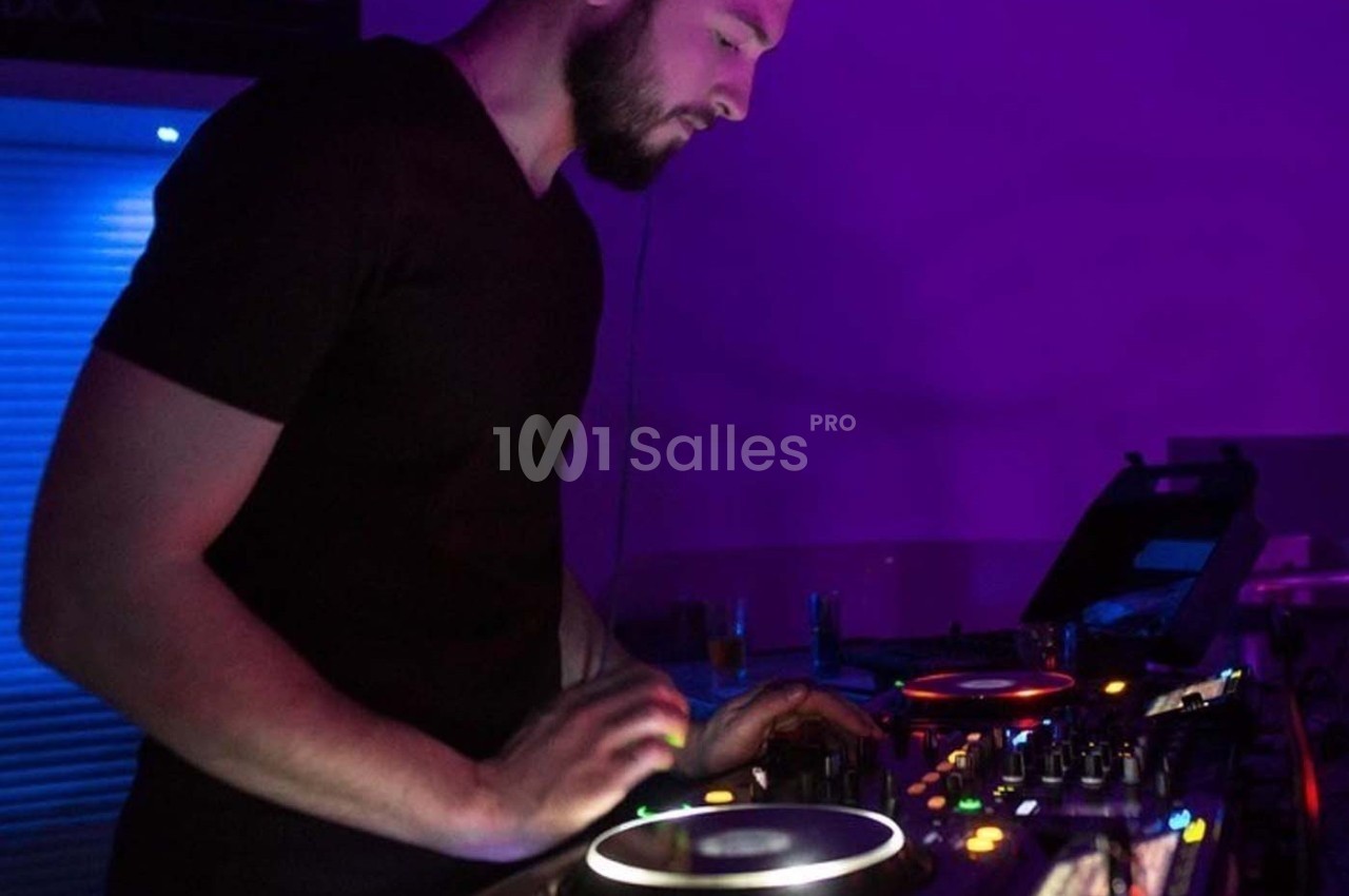 Un DJ mixant de la musique sur une table de mixage dans une ambiance lumineuse violette.