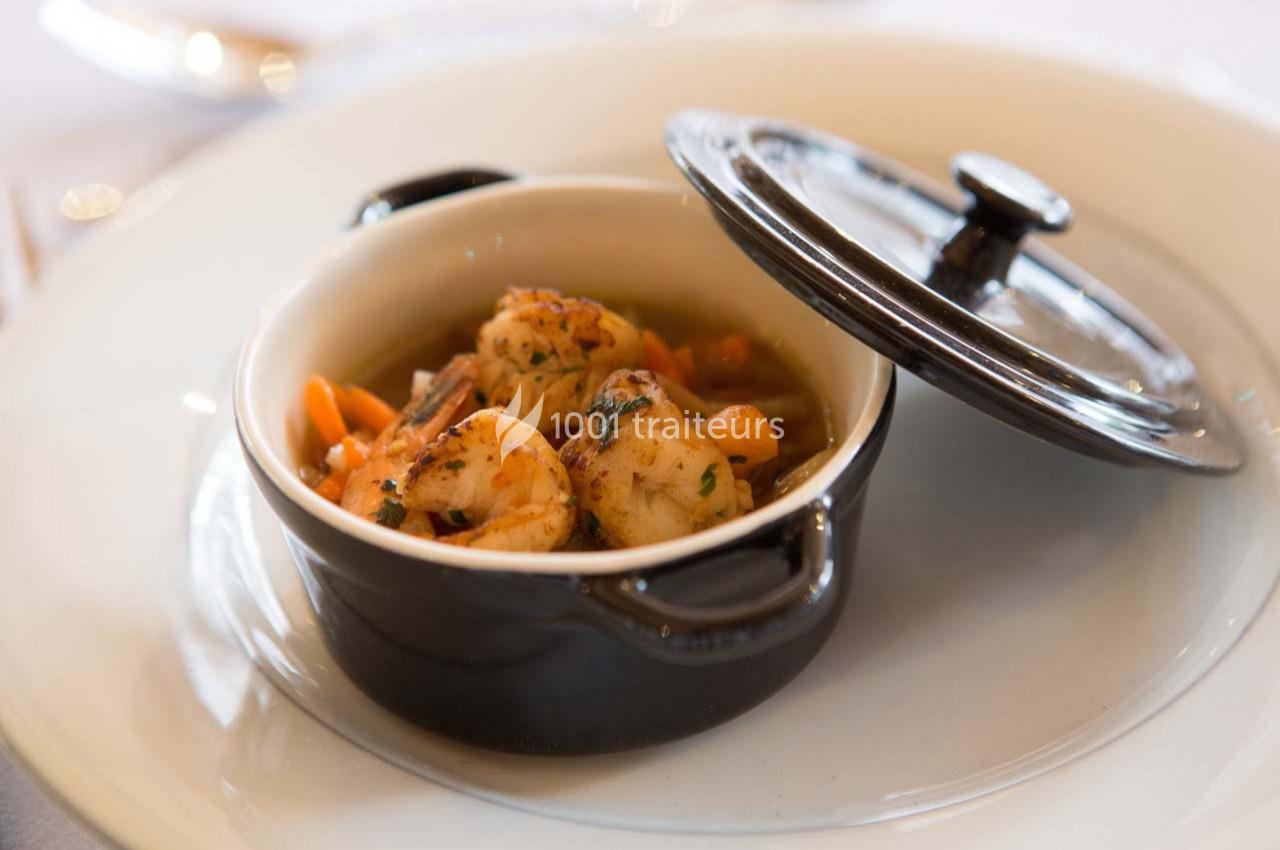 Crevettes sautées aux herbes servies dans une petite cocotte noire avec des légumes.