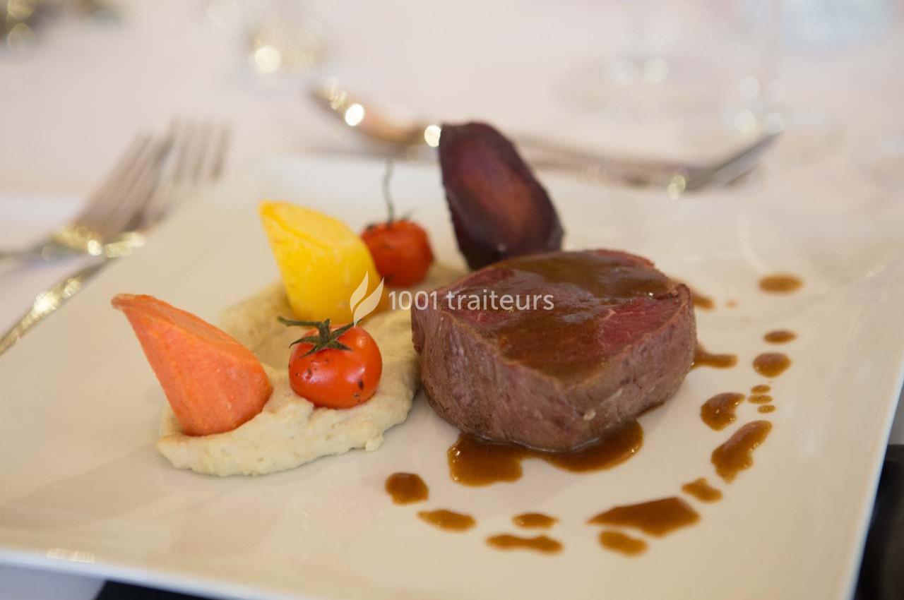 Assiette de viande sauce brune, purée, légumes colorés et tomate cerise, servie sur une table dressée.