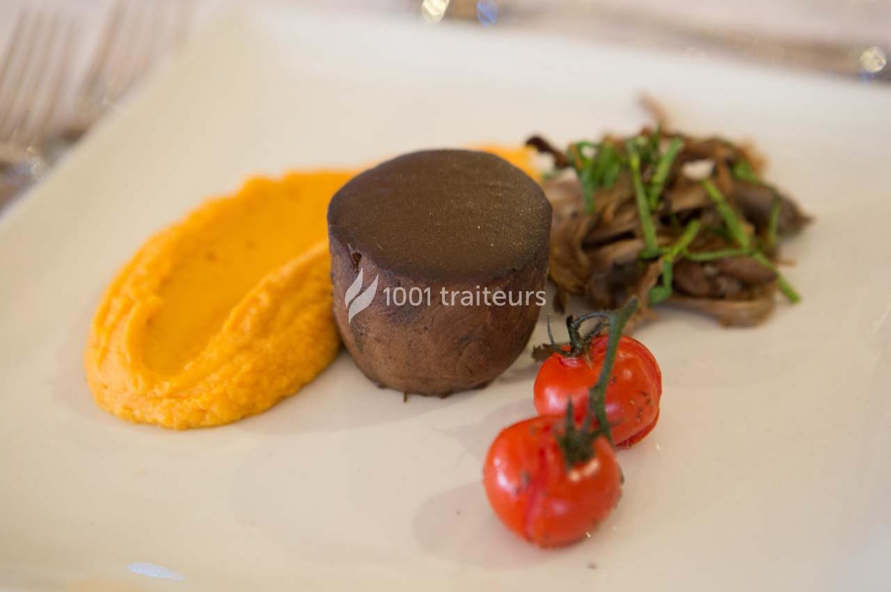 Assiette avec purée orange, pièce de viande, champignons sautés et tomates cerises grillées.
