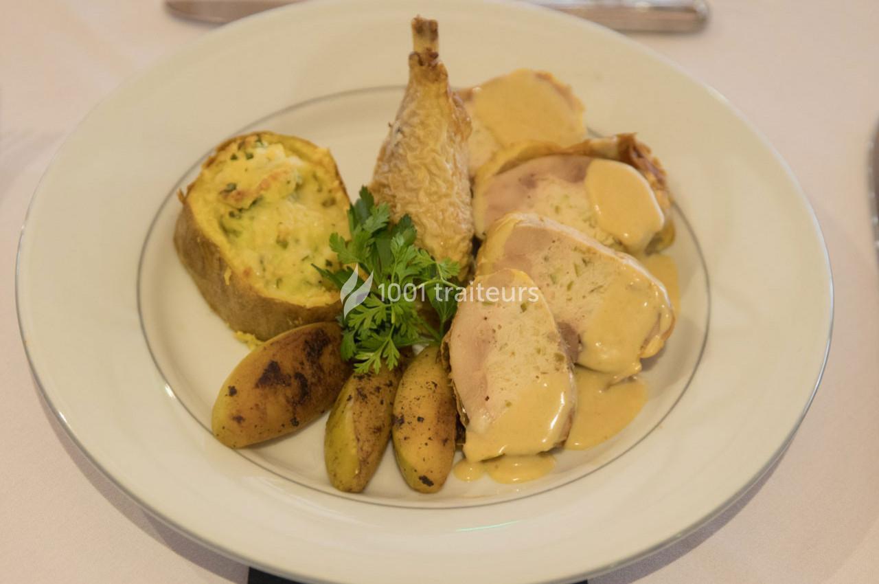 Assiette composée de volaille en sauce, pommes de terre rôties, flan de légumes et garnie de persil frais.