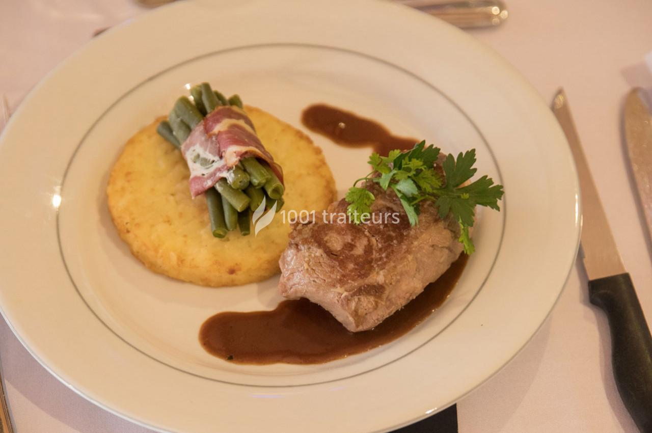 Assiette composée d'un médaillon de viande, d'une galette de pommes de terre, de haricots verts enroulés de lard et d'une…