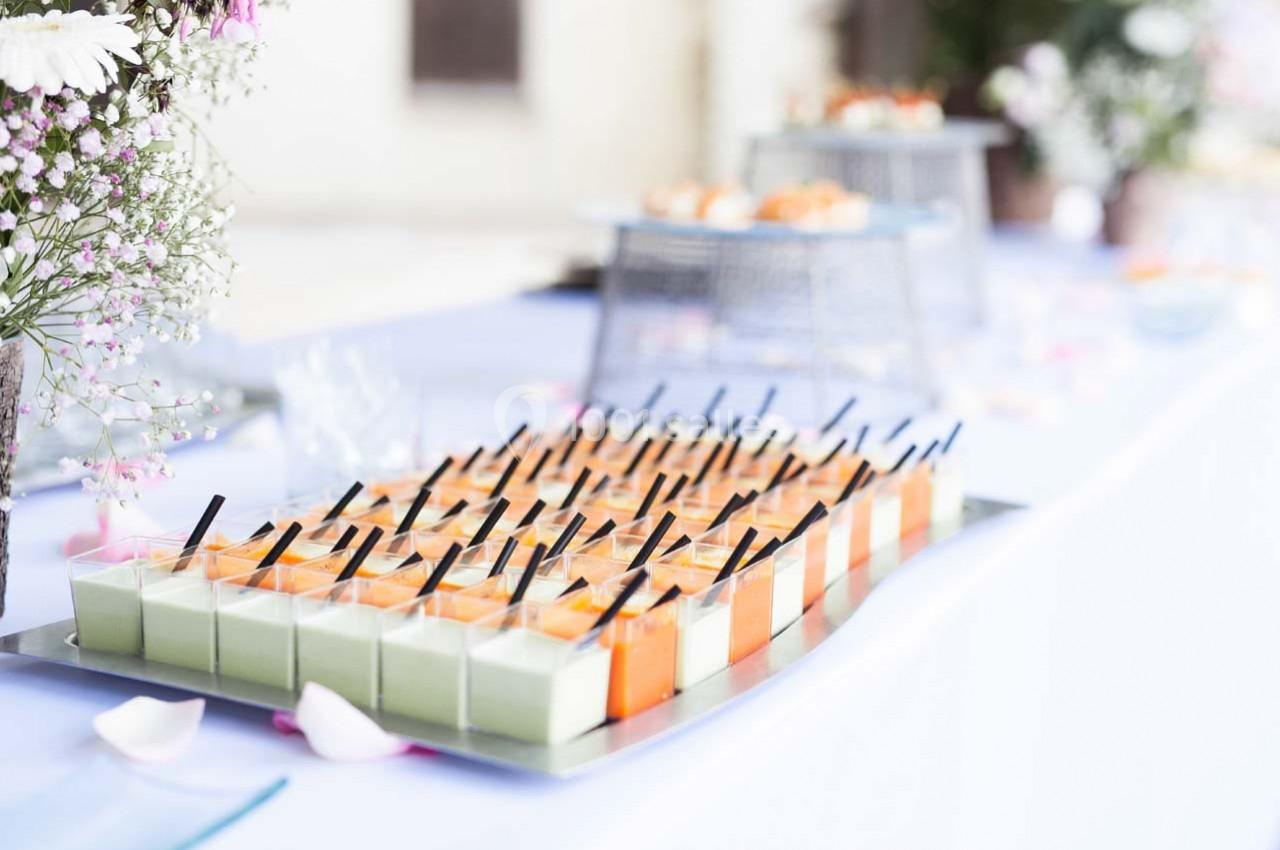Plateau de verrines colorées disposées sur une table blanche, entouré de fleurs et de décorations élégantes.