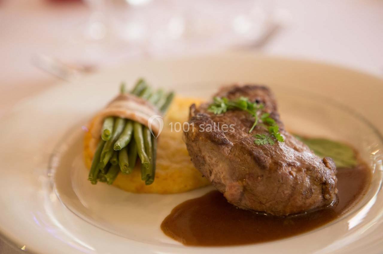Assiette contenant un filet de viande avec sauce, accompagné de haricots verts liés et d'une galette de pommes de terre.