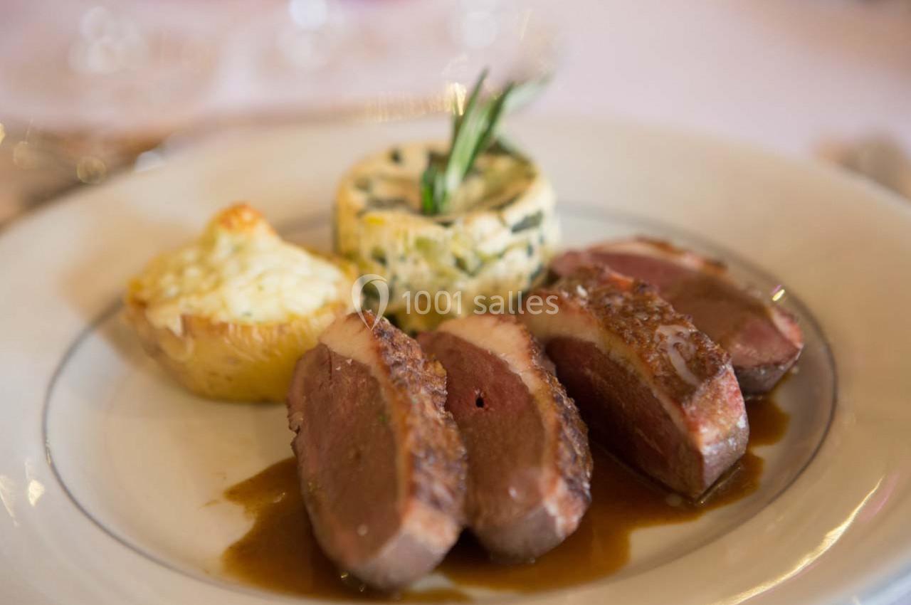 Assiette contenant des tranches de viande sauce, un gratin de pommes de terre et un flan aux herbes.