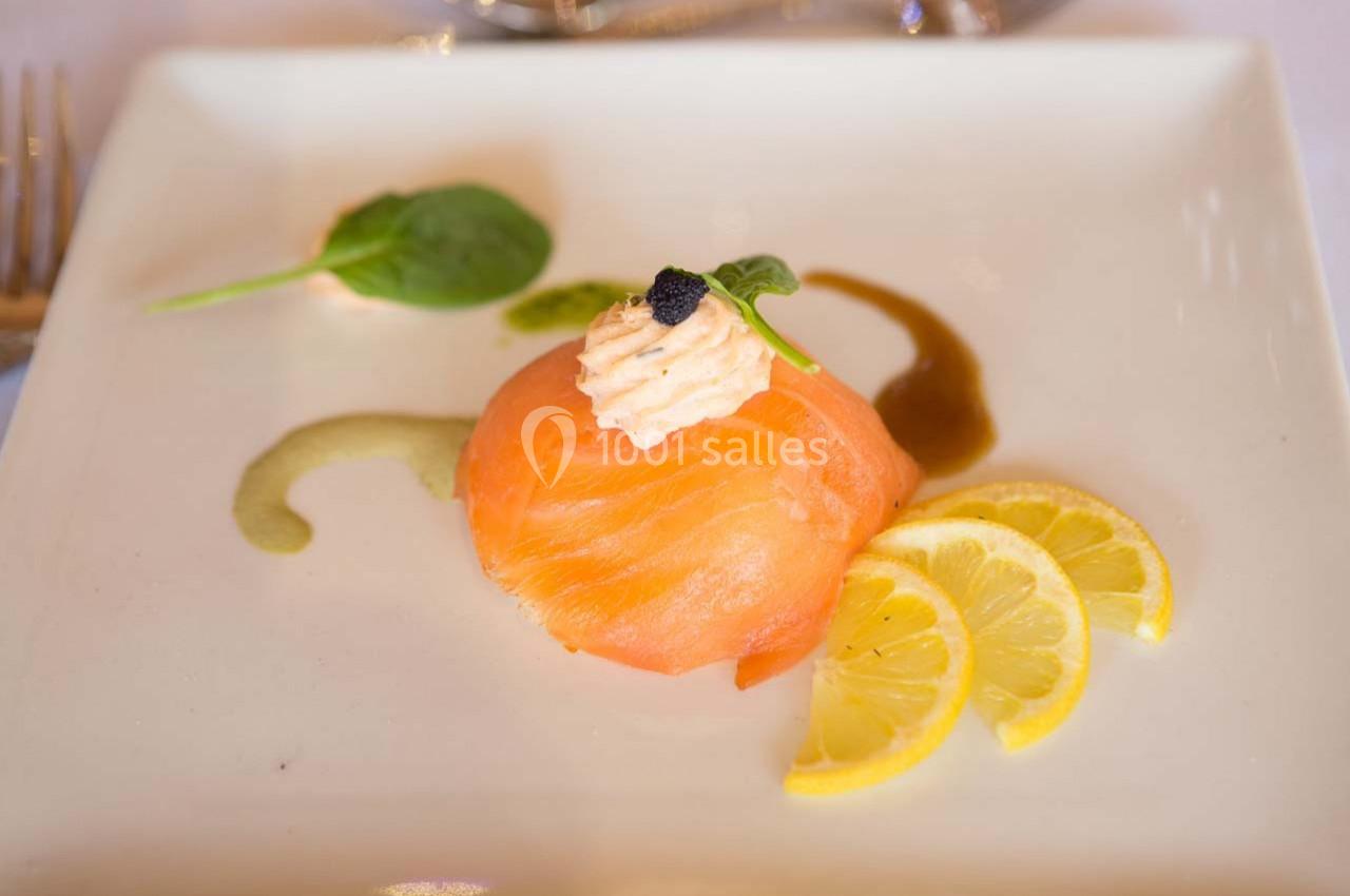 Tranche de saumon fumé garnie de crème, caviar et feuille de roquette, accompagnée de rondelles de citron.