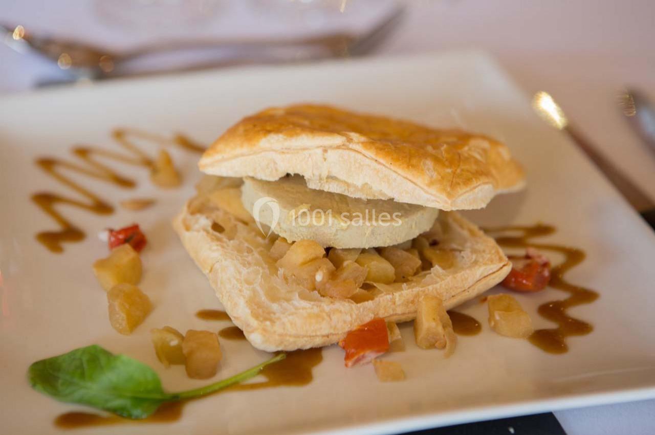 Feuilleté garni de foie gras et pommes caramélisées, accompagné de sauce décorative et d'une feuille de salade.