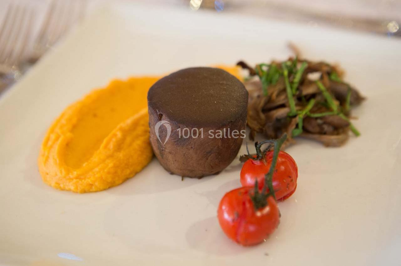 Assiette gastronomique avec purée de carottes, pièce de viande, champignons sautés et tomates cerises grillées.