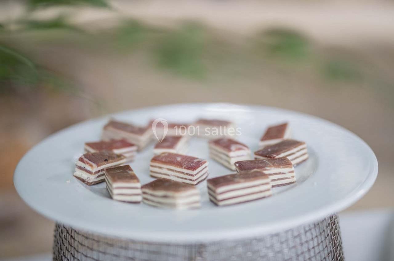 Assortiment de petits gâteaux en couches blanches et brunes disposés sur une assiette blanche.