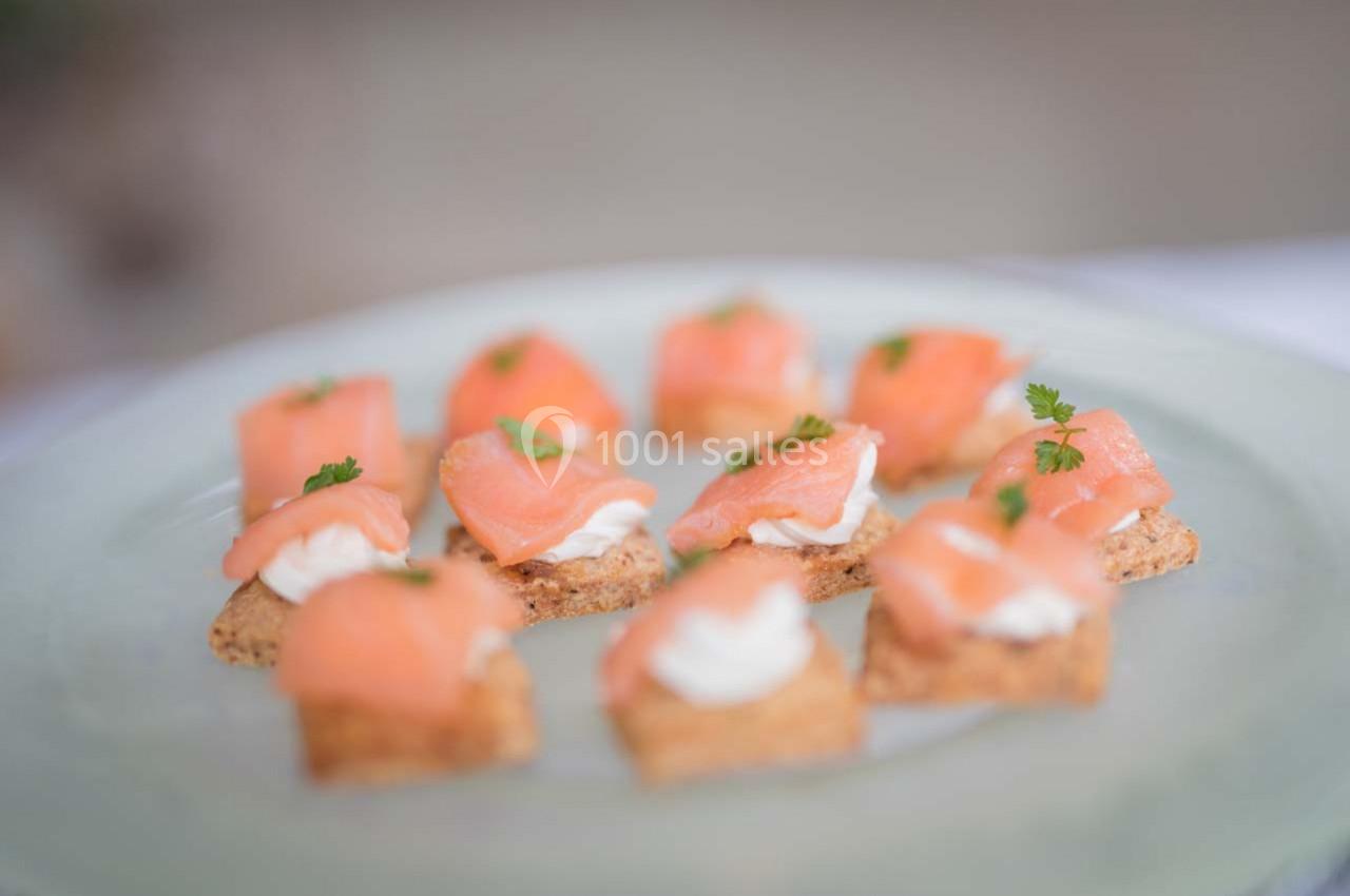 Assortiment de canapés au saumon fumé, garnis de crème et décorés de brins de persil sur une assiette claire.