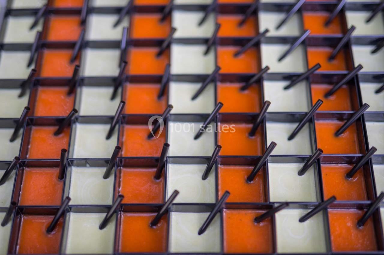 Grille métallique avec des tiges verticales, posée sur un fond alternant carreaux orange et beige.