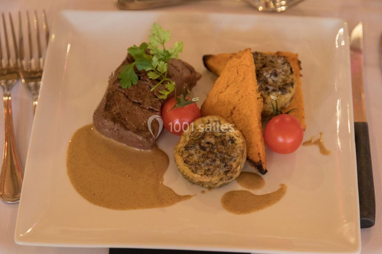 Assiette contenant une pièce de viande, sauce, légumes grillés, tomates cerises et garniture aux champignons.